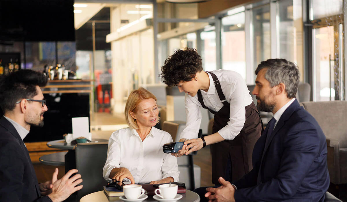 A server taking payment with an EFTPOS device at a table in a restaurant