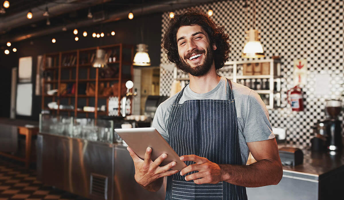 A restaurant owner holding a tablet in his restaurant