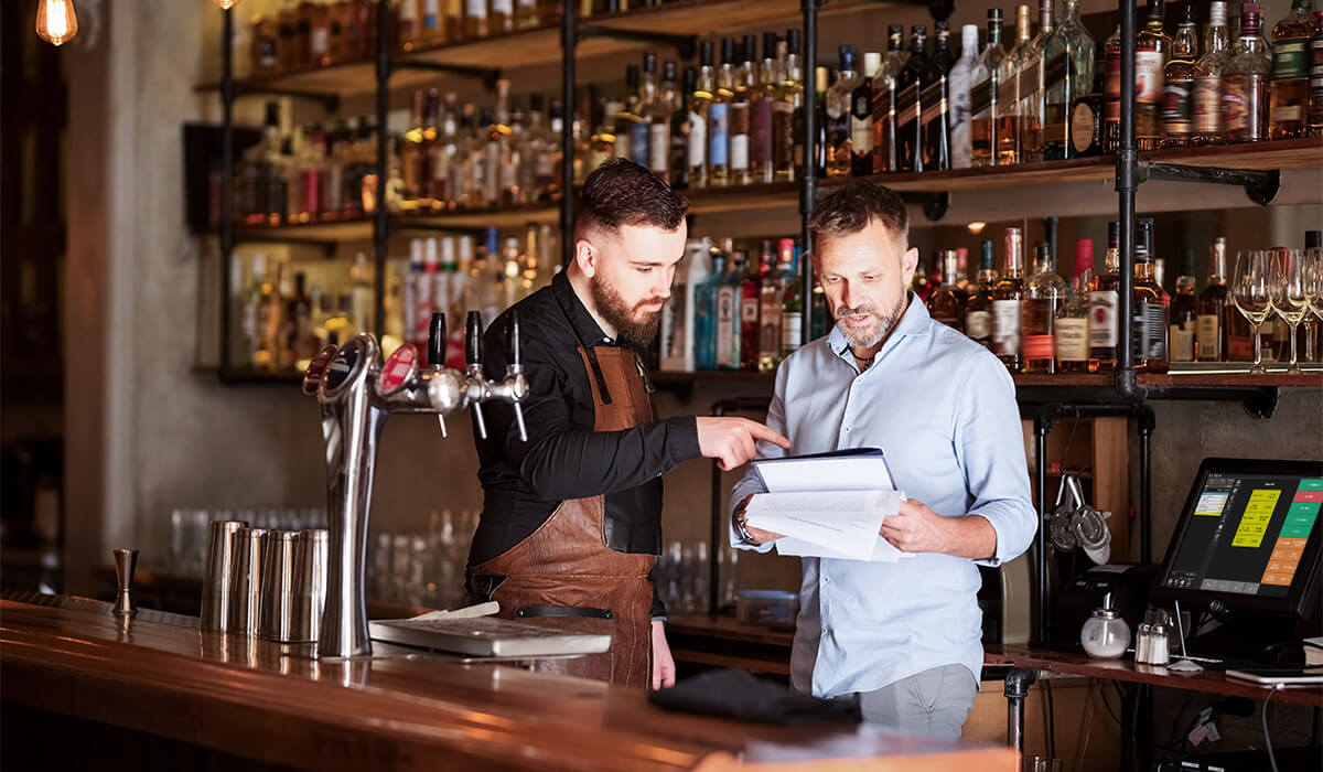 A bar owner and a bar manager checking over paperwork in a bar
