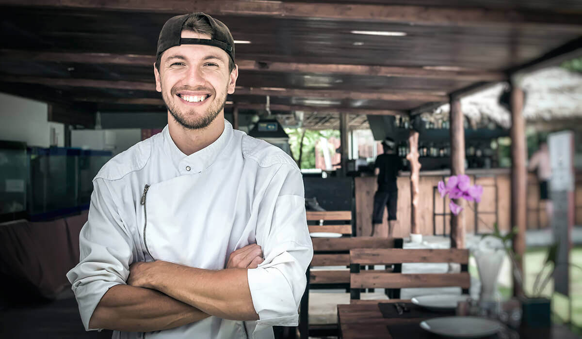 A chef smiling at the camera in his outdoor venue