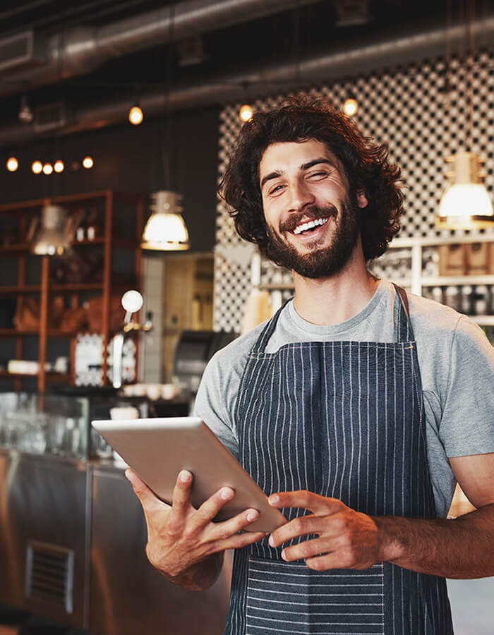 A restaurant owner holding a tablet in his restaurant